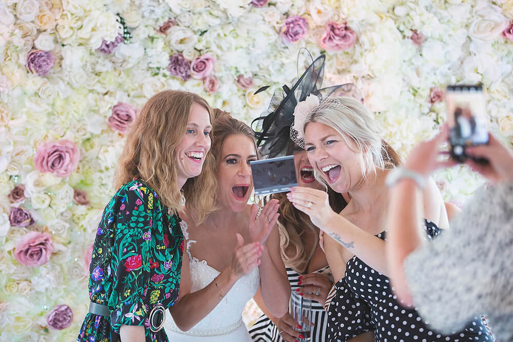 A bride and her girlfriends laughing at a photo at a wedding at Parley Manor, Christchurch.